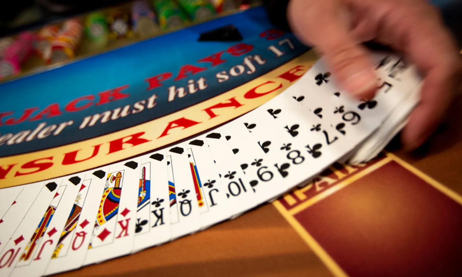 dealer hands fanning out deck of cards at blackjack table