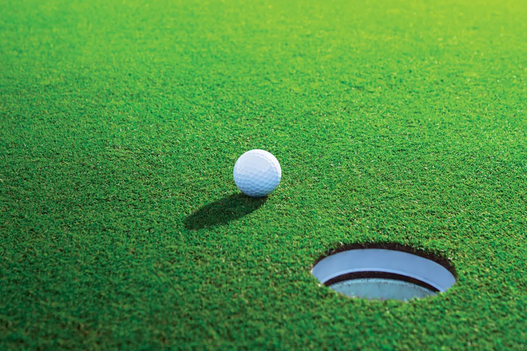 Golf ball setting next to hole