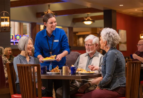 Man and two women being served breakfast by a waitress