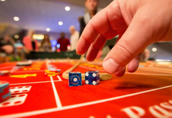 hands grabbing for dice sitting on red craps table
