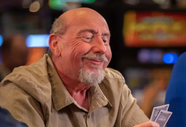 Man grinning a pair of cards in his hand 