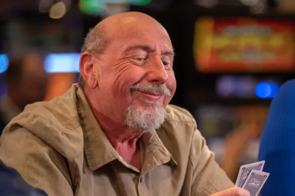 Man grinning a pair of cards in his hand 