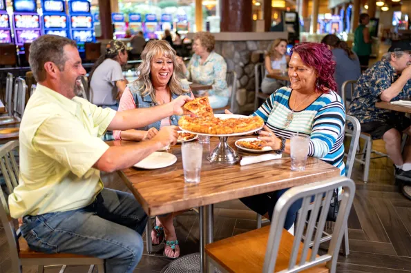 man and two women sitting around a table eating pizza