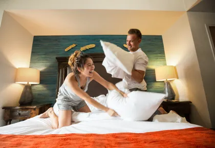 Two guests enjoying a playful pillow fight in a hotel room at Little River Casino Resort in Manistee, Michigan