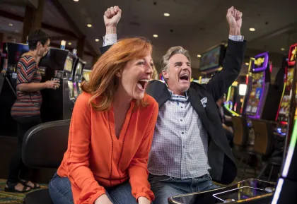 Two guests celebrating a win at a slot machine inside Little River Casino Resort in Manistee, Michigan