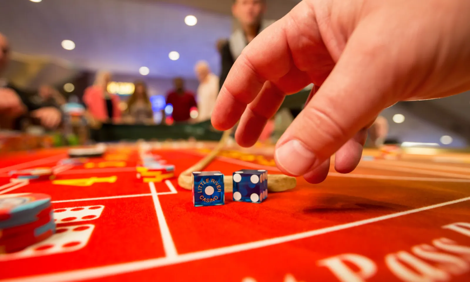 hands grabbing for dice sitting on red craps table