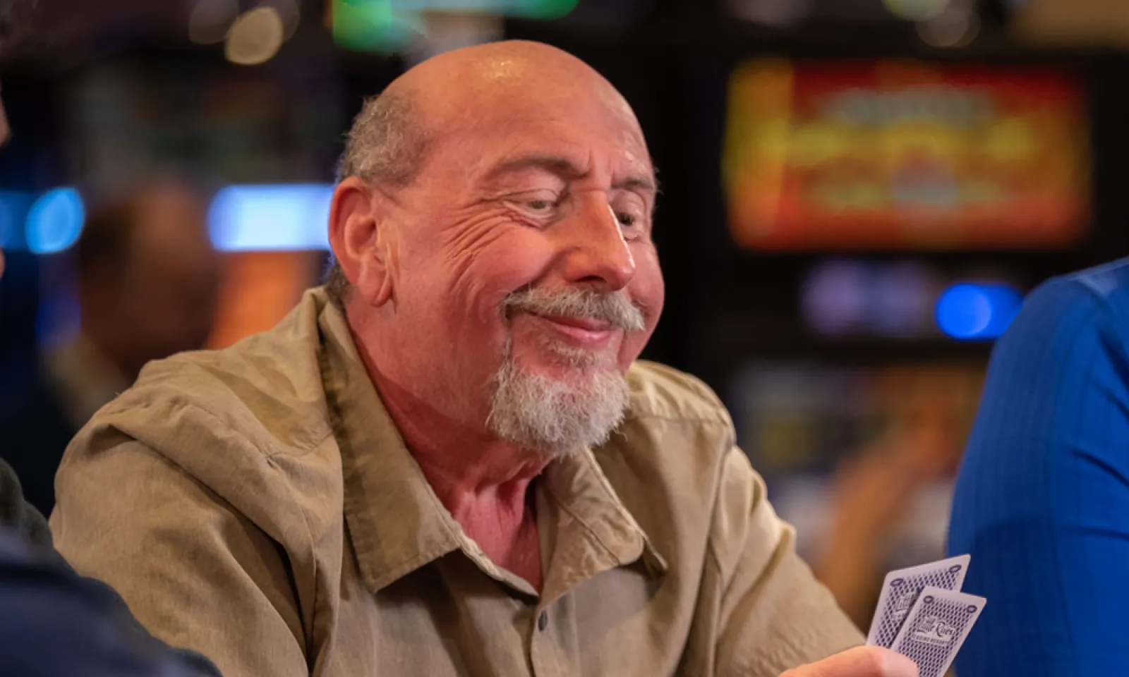 Man grinning a pair of cards in his hand 